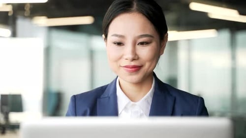 Smiling Businesswoman Using Laptop in Modern Office