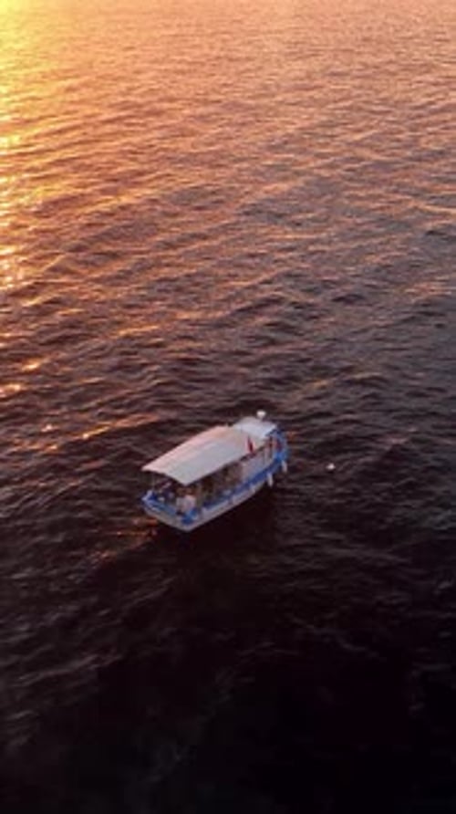 Vidéo verticale : vue aérienne, bateau de pêche et reflets de la mer au coucher du soleil
