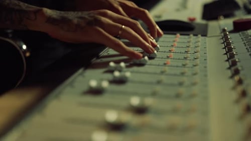 Sound Engineer Adjusting Console Sliders