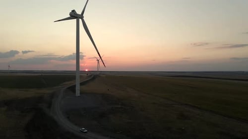 Windmills Generate Electric Power at Sunset in a Calm Windmill Park Promoting Green Energy