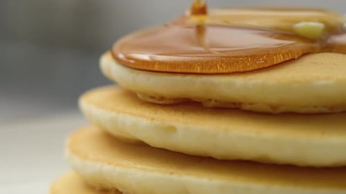 Close-Up of Maple Syrup Pouring Over Pancakes. with Red