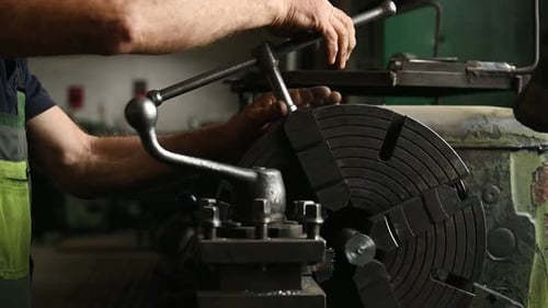 Close-up of worker's hands operating industrial machinery in workshop.