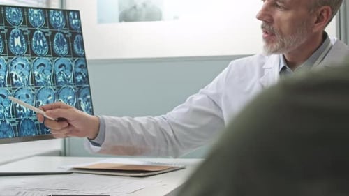 Doctor Consulting with Patient Over MRI Scan in Clinic