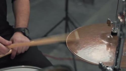 Drummer's Hand with a Watch Hitting a Brass Cymbal During an Energetic Live Performance in an