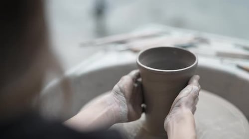 Young women is making earthenware at workshop.