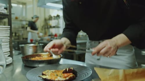 Restaurant Chef Serving Fish with Eggplant at Sauce on Plate in Kitchen