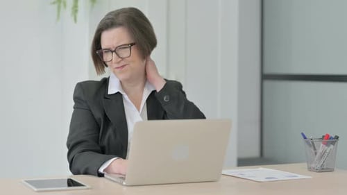 Businesswoman Massaging Stiff Neck at Desk in Office