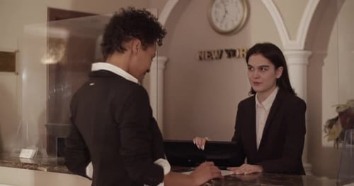 Diverse Female Tourist and Concierge Communicating at Hotel