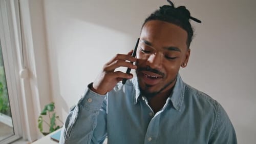 Young Man Talking on Phone Indoors Near Window