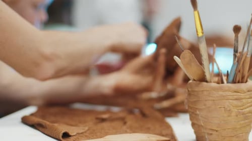 Hands Shaping Clay in Art Studio Setting