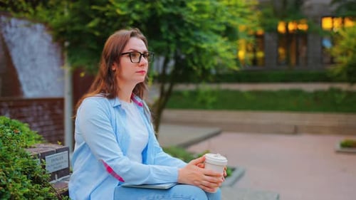 Portrait of Woman Standing on the Street with Laptop and Coffee in Hands