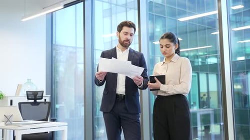 Professional business meeting between two financiers in modern office, discussing important document