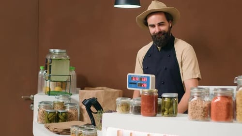 Man Stands Behind Counter in Food Shop