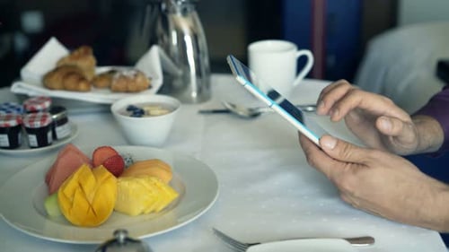 Businessman Hands with Tablet Computer by the Table During Breakfast Alone