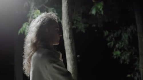 Side View Woman Walking Away From Street Light in Darkness