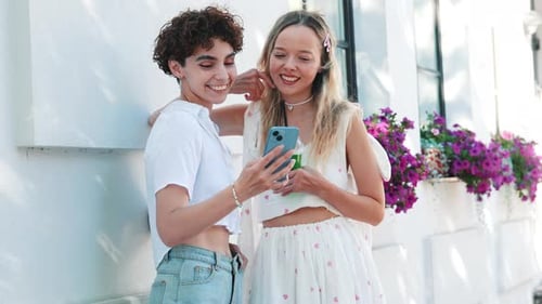 Two Friends Looking at Phone on City Street