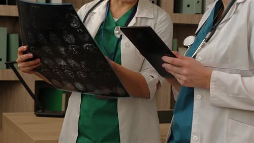 Closeup of Females Doctors with Tablet Pc Examining MRI Brain Scan at Clinic