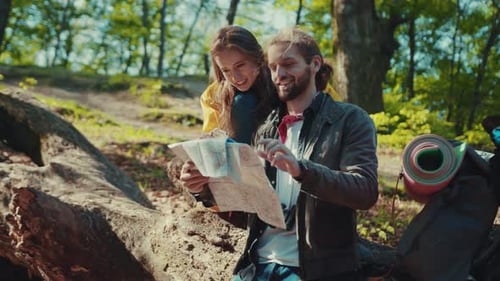 Couple Hiking and Reading Map in Forest