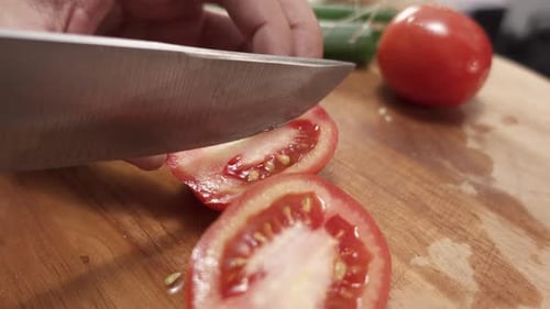 Slicing Fresh Tomato with Sharp Knife on Board