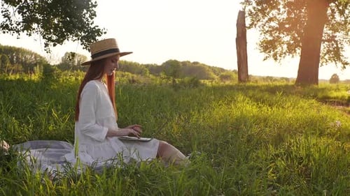 Woman Working On Laptop in Rural Grassy Field