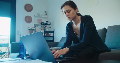 Woman Using Laptop on Couch Indoors