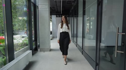 Professional Woman Walking Confidently in Office Corridor Businesswoman Strides Forward in Office