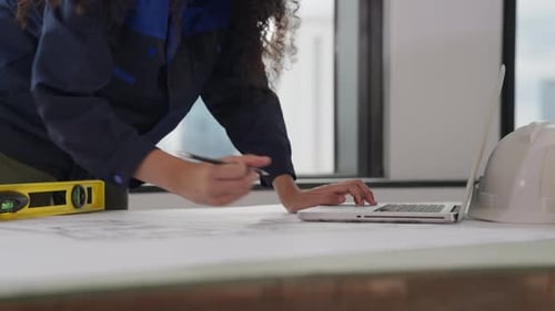 Female Architect with Yellow Helmet Drawing on Blueprint