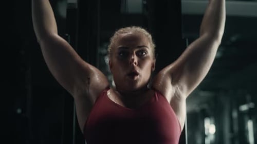 Retrato de una mujer fuerte haciendo ejercicios de levantamiento de pesas con una máquina Lat Pull Down en un Obsc