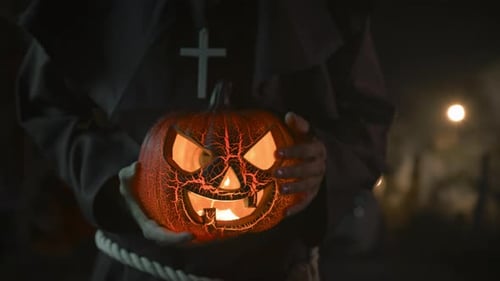 Mysterious Figure Holding Glowing Jack-o'-Lantern at Night