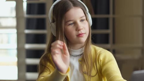 A Young Girl Listens to Music with Headphones Casually Holding One Side in Place She Appears Relaxed