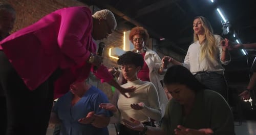 Leader guiding women in prayer circle, hands raised, joining in spiritual bonding,