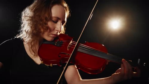 Woman Plays Violin in Dark Studio