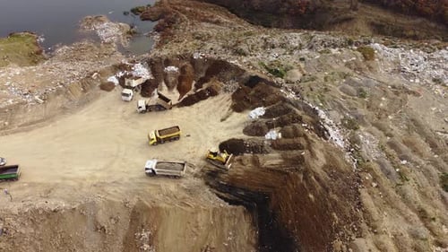 garbage and big trailers throuing in field of garbage