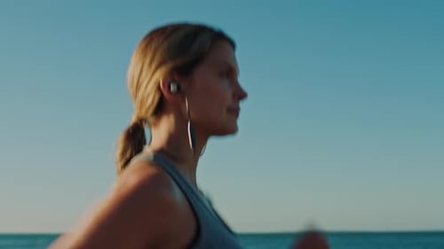 Beach, earphones and woman running for exercise, health and wellness