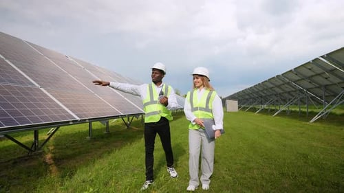 Two Multiracial Engineers Walking in Solar Station Checking Solar Panels Setup