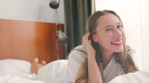 Smiling Woman Relaxing on Hotel Bed