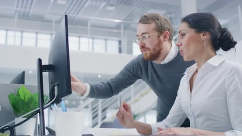 Man and Woman Collaborating on Computer in Office