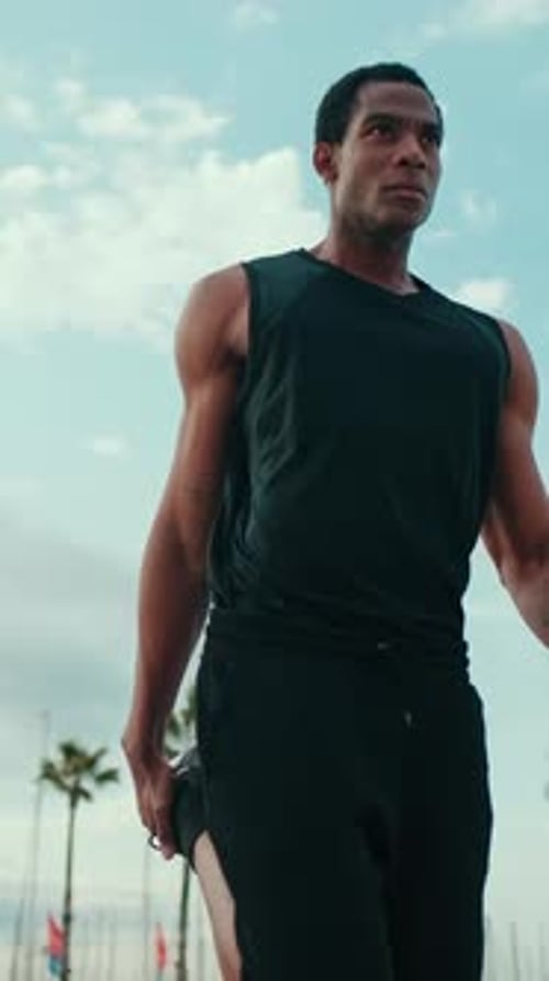 Vertical video, Man Stretching Before a Run on the Beach
