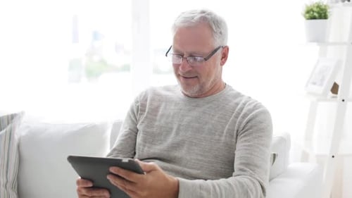Senior Man Relaxing on Sofa with Tablet Computer