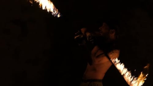 Man Spinning Fiery Sticks at Night