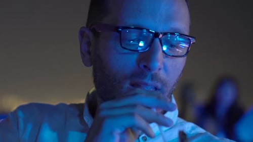 Young, Happy Man Drinking Cocktail Sitting On Terrace In Bar At Night