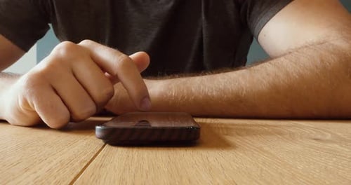 Man Tapping Smartphone on Table