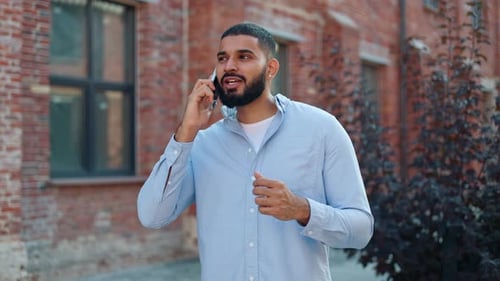 Casually Dressed Man Talking on Mobile Phone Near Brick Building Outdoors