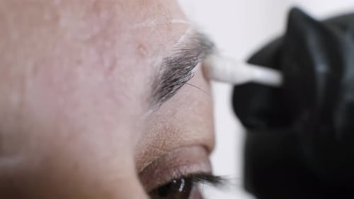 Gloved Hand Swabbing Eyebrow of Adult