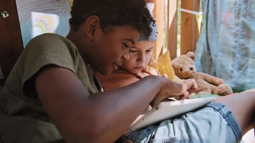 Two Children Use Tablet in Cozy Play Area