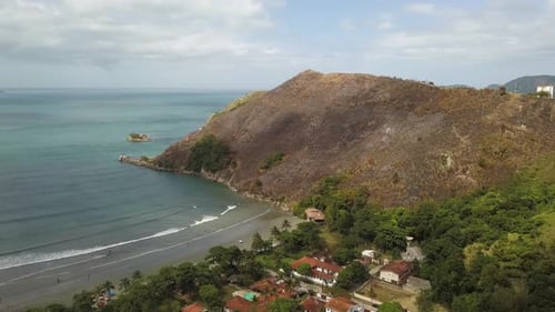 Coastal city near mountain that had part of its vegetation devastated by fire. Aerial