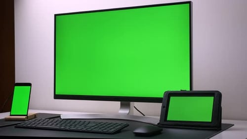 Modern Personal Computer, tablet and phone with Mock-up Green Screen Display Standing on the Desk of