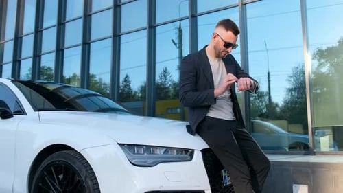A Young Rich Businessman in a Suit Standing Near His Luxury Car