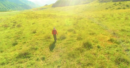 Flight Over Backpack Hiking Tourist Walking Across Green Mountain Field Huge Rural Valley at Summer