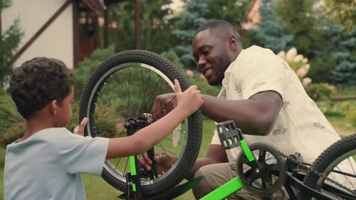 Father and Son Repairing Bike Together Outdoors